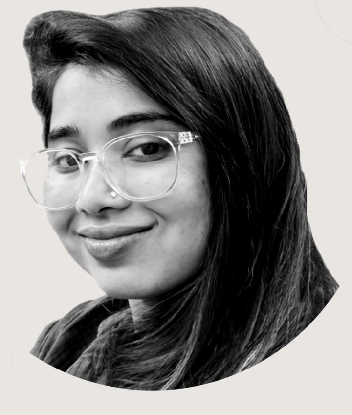 Karishma, smiling, wearing clear-framed glasses