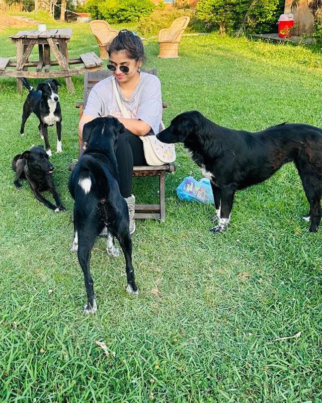 Karishma with four black dogs on a lawn